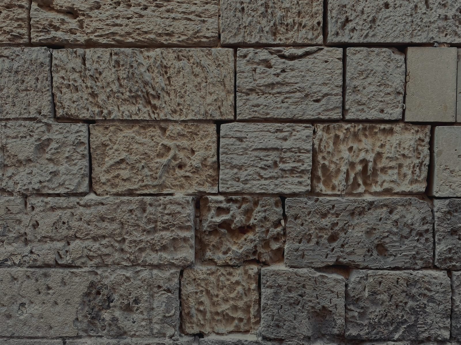 Courses of cut limestone blocks, each face weathered differently.